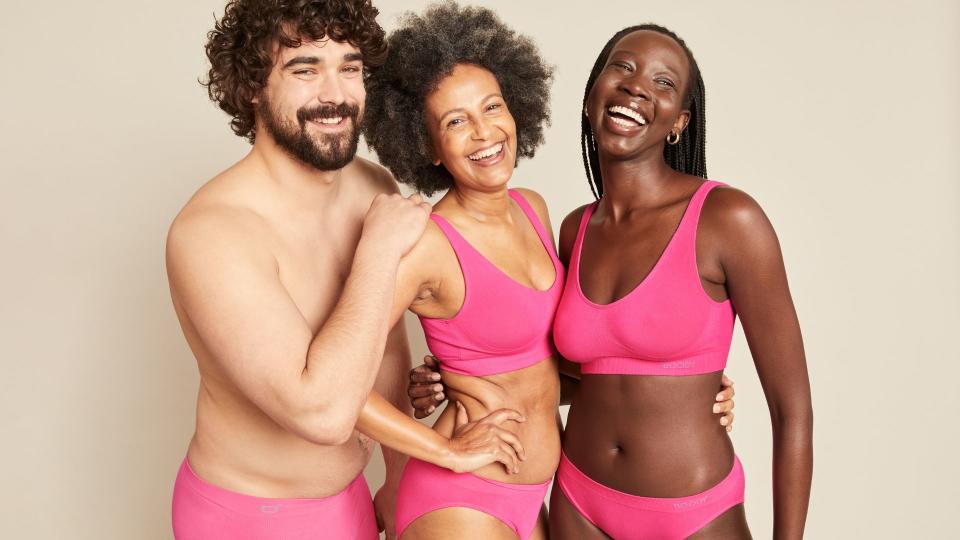 A man and two women in bright pink underwear by Boody for Cancer Awareness Month.