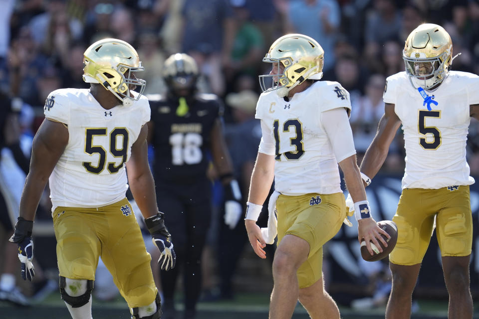 Notre Dame quarterback Riley Leonard (13) celebrates his touchdown down with teammates Aamil Wagner (59) and Beaux Collins (5) during the first half of an NCAA college football game against Purdue in West Lafayette, Ind., Saturday, Sept. 14, 2024. (AP Photo/Michael Conroy)