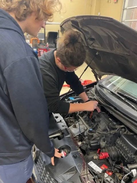 Dakota Hutcheson and Justin Morris change oil in a car at Effingham College and Career Academy as part of the school's automotive program.