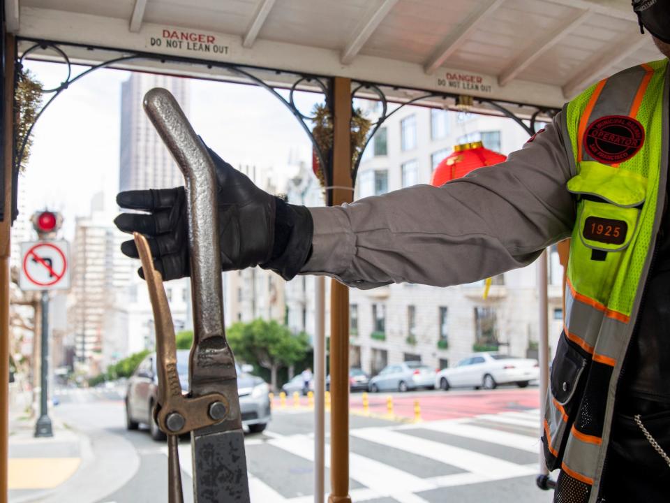 SFMTA Gripman Val Lupiz steers a cable car adorned in Lunar New Year decorations while it's pulled up Powell Street by a semi-truck due to the lack of cable in San Francisco, Calif. Thursday, February 18, 2021.