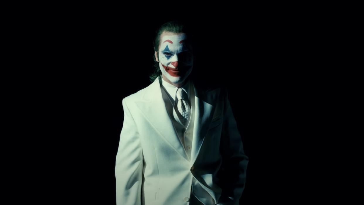  Joaquin Phoenix in Joker clown makeup wearing white suit. 