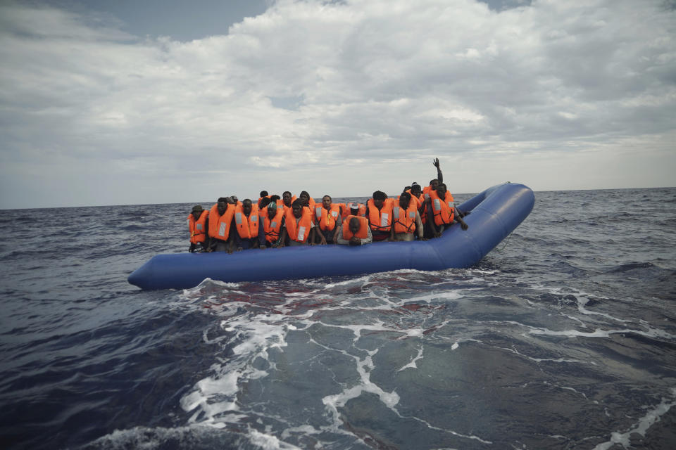 A migrant waves his hand in the air from on a blue rubber boat some 14 nautical miles from the coast of Libya in Mediterranean Sea, Sunday, Sept. 8, 2019. Humanitarian groups SOS Mediterranee and Doctors Without Borders have successfully rescued 50 migrants and brought them aboard the Ocean Viking. (AP Photo/Renata Brito)