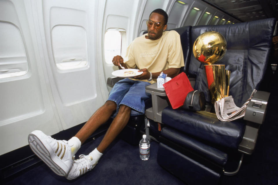 Kobe casually eats an in-flight meal with the NBA Championship trophy beside him. Of course, plenty of leg room provided for his size-14 Adidas. (Photo: Getty Images)