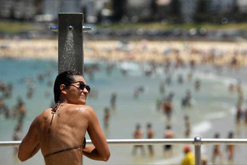 A woman uses a shower after a swim during heatwave conditions at Bondi Beach in Sydney.