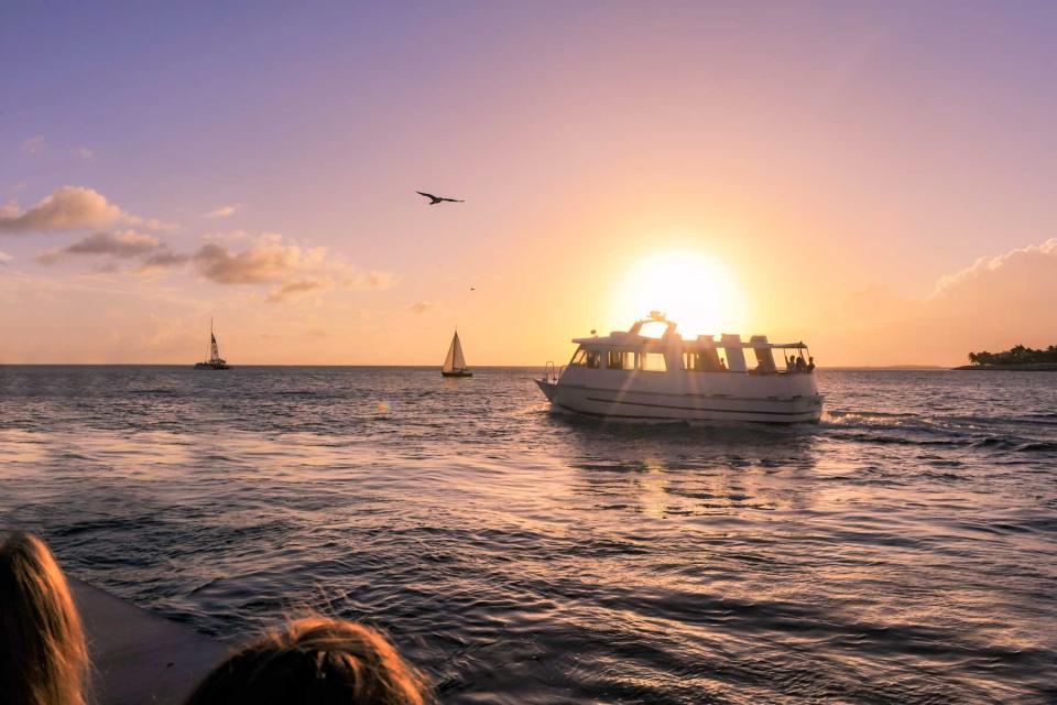 People gather at Mallory Square in Key West to see the sunset as boats go by on the water