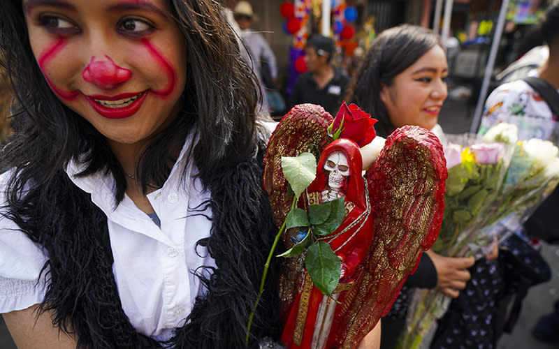 A devotee holds an ornately decorated statue of Nuestra Señora de la Santa Muerte