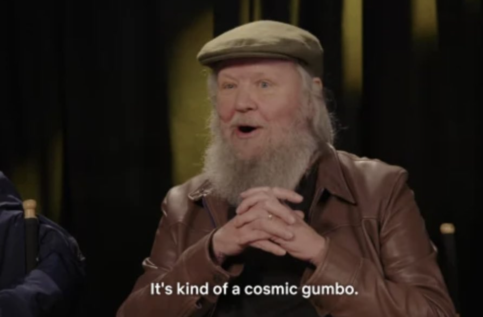 a man with a beard and paperboy hat crosses his hands and says "it's kind of a cosmic gumbo"