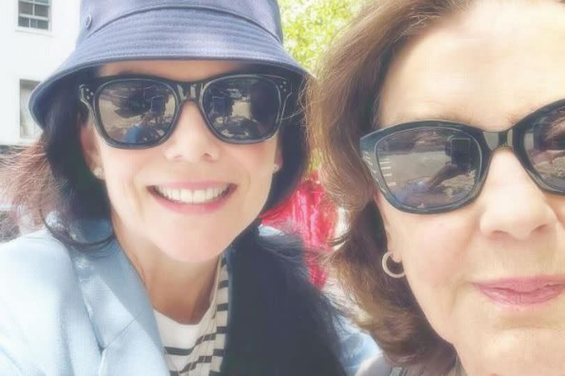 Lauren and Kelly smile in a selfie, which only features 3/4 of Kelly's face. Both the women are wearing black sunglasses.