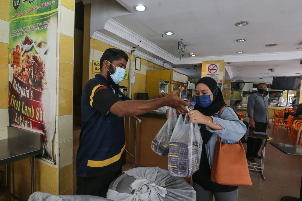 A customer packs food to go at Syed Bistro Restaurant in Puchong June 14, 2021. — Picture by Yusof Mat Isa