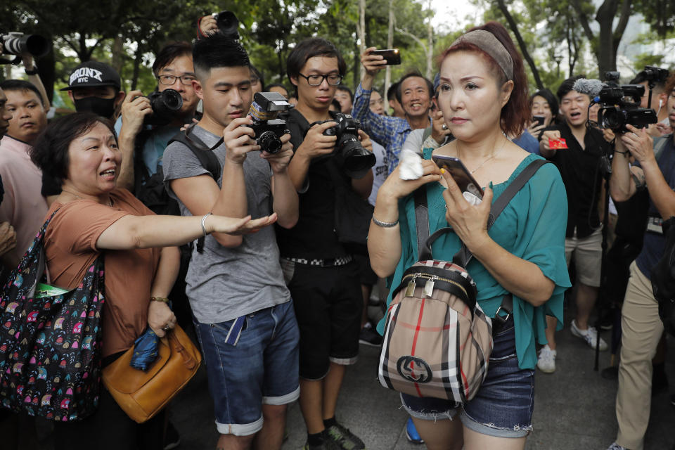 A woman, left, throws a tissue paper to a Chinese street performer, right, at the Tuen Mun Park, in Hong Kong, Saturday, July 6, 2019 as hundreds of protesters gathered, protesting against mainland Chinese singers causing nuisance to the local neighborhood. The extradition protest sparked Hong Kong netizen to line more protest during the weekend, with focus on some local conflicts between mainland Chinese and Hong Kongers. The extradition protest sparked Hong Kong netizen to line more protest during the weekend, with focus on some local conflicts between mainland Chinese and Hong Kongers. (AP Photo/Kin Cheung)