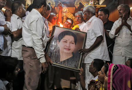 Well wishers of Tamil Nadu Chief Minister Jayalalithaa Jayaraman hold her portrait as they pray at a temple in Mumbai, India, December 5, 2016. REUTERS/Danish Siddiqui
