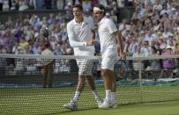 Roger Federer of Switzerland (R) puts an arm around Milos Raonic of Canada after defeating him in their men's singles semi-final tennis match at the Wimbledon Tennis Championships, in London July 4, 2014. REUTERS/Facundo Arrizabalaga/Pool (BRITAIN - Tags: SPORT TENNIS)