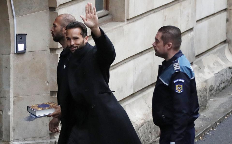 Tristan Tate waves as he and his brother are escorted by Romanian police officers inside the Court of Appeal - Robert Ghement/EPA-EFE/Shutterstock