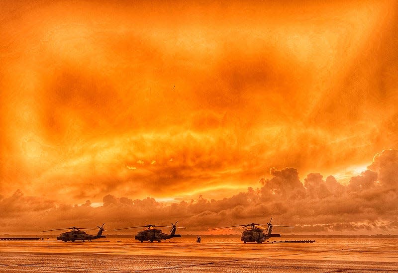 Three MH-60R Sea Hawk helicopters line the seawall at Naval Air Station Jacksonville as the sun rises over the St. Johns River.