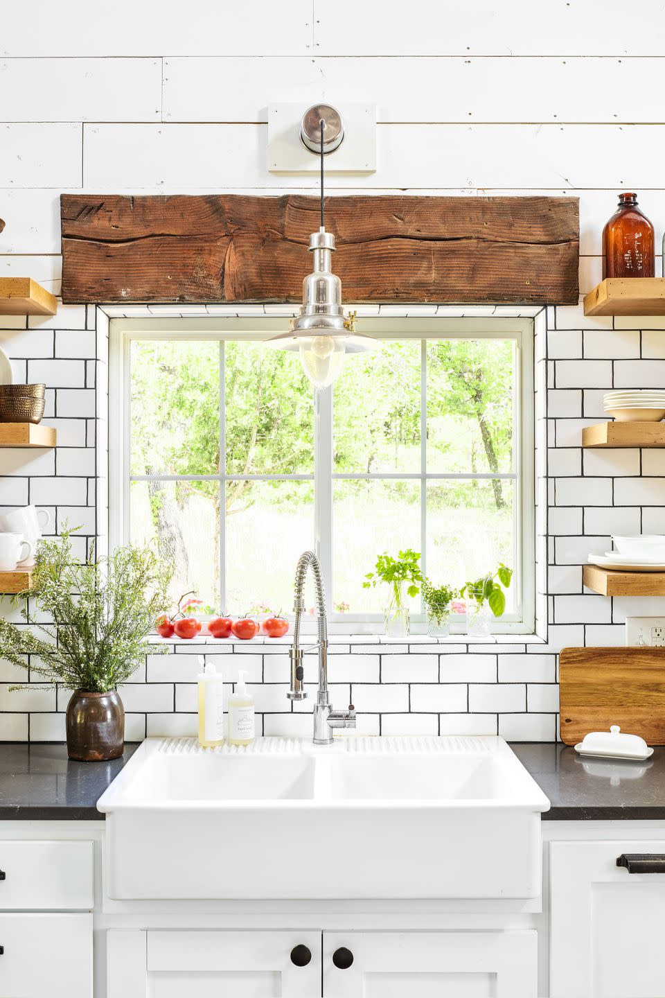 farmhouse style white kitchen sink and tile backsplash and fresh veggies in a window sill