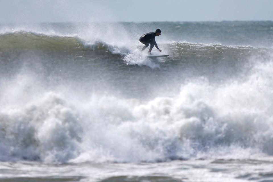 A surfer rides a big wave caused by Hurricane Lee, at Horseneck Beach in Westport