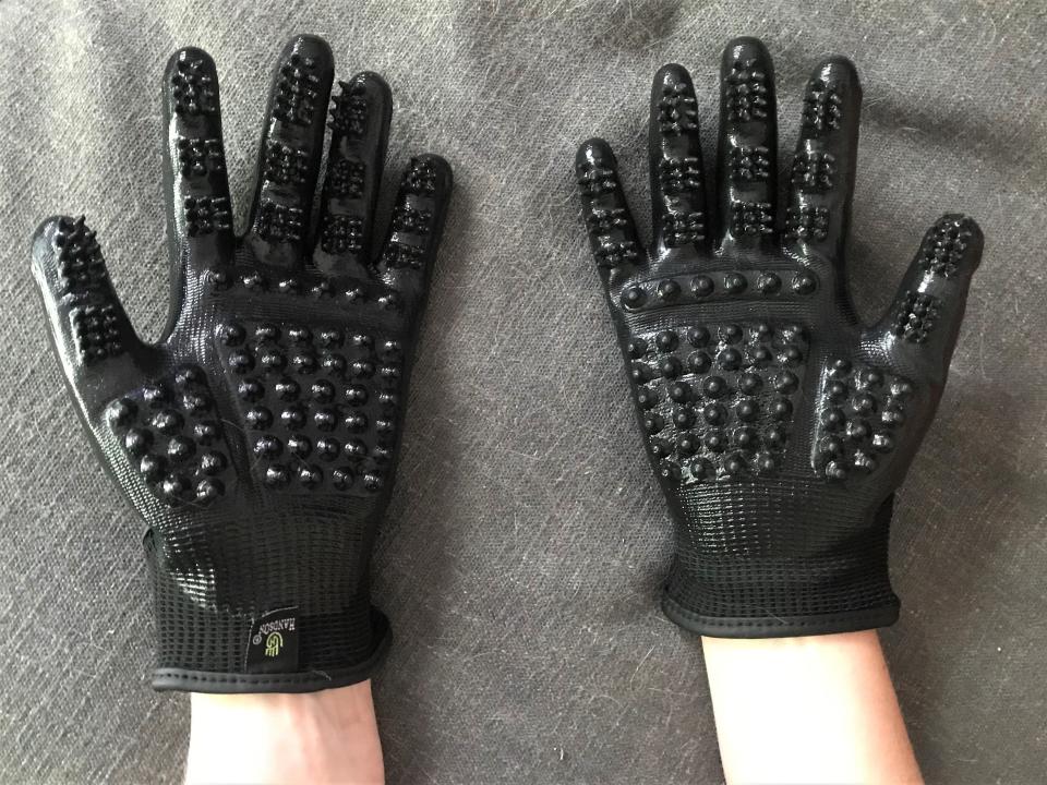 Palms of two hands shown wearing black HandsOn cat grooming gloves.