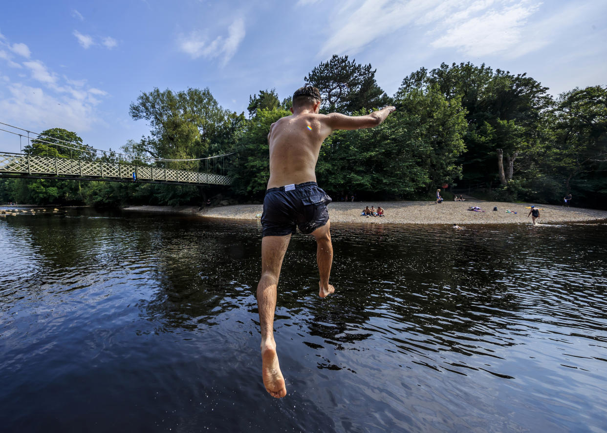 A person jumps from a rock into the River Wharfe near Ilkley in Yorkshire, as people continue to enjoy the hot weather. (Photo by Danny Lawson/PA Images via Getty Images)