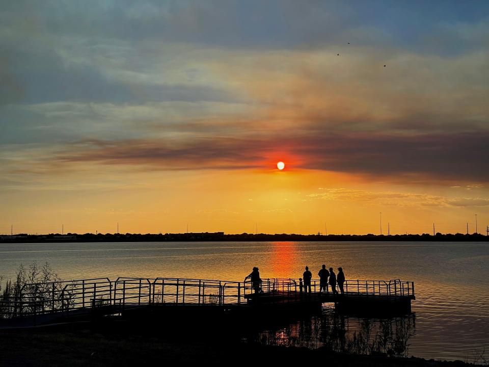 People wait for air tankers to scoop water from Kirby Lake as a smoke cloud from a wildfire south east of Abilene hangs before the sun Friday.