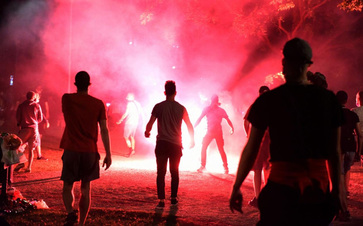 Protesters light flares as they attend a rally against the government's lockdown measures in front of the parliament in Belgrade, Serbia - Reuters