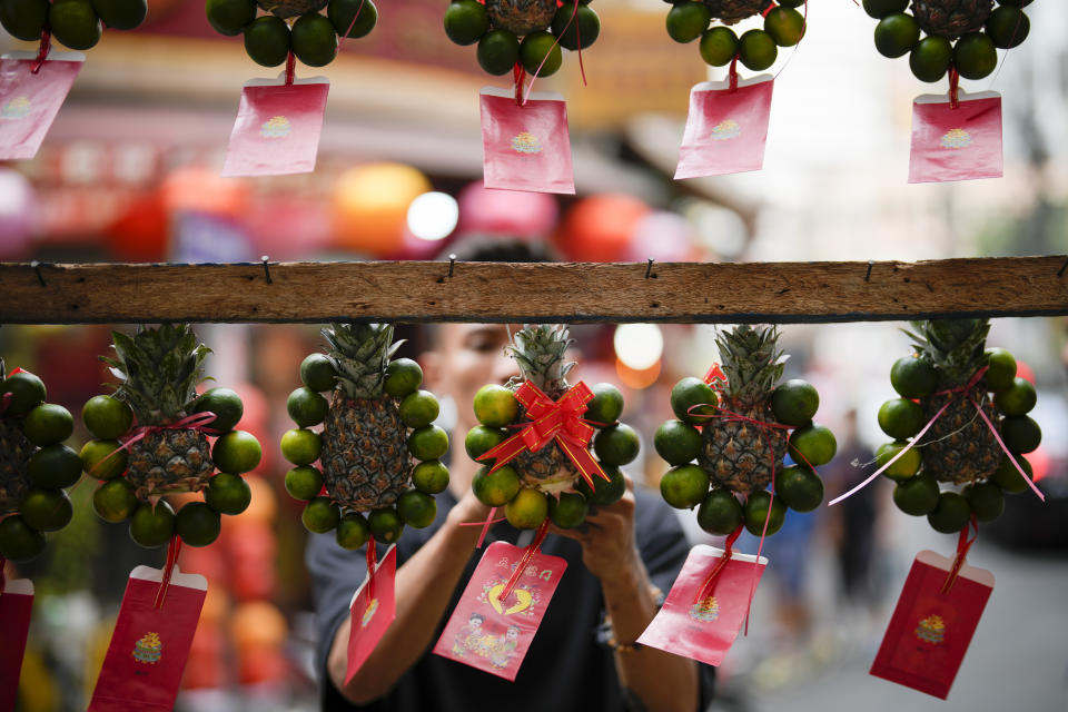 A vendor sells fruits with lucky charms for the coming Chinese New Year at Binondo district, said to be the oldest Chinatown in the world, in Manila, Philippines on Monday, Feb. 5, 2024. Crowds are flocking to Manila's Chinatown to usher in the Year of the Wood Dragon and experience lively traditional dances on lantern-lit streets with food, lucky charms and prayers for good fortune. (AP Photo/Aaron Favila)