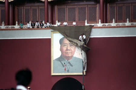 FILE PHOTO: Workmen try to drape the portrait of Mao Zedong in Tiananmen Square in Beijing, China, May 23, 1989. REUTERS/Ed Nachtrieb/Files