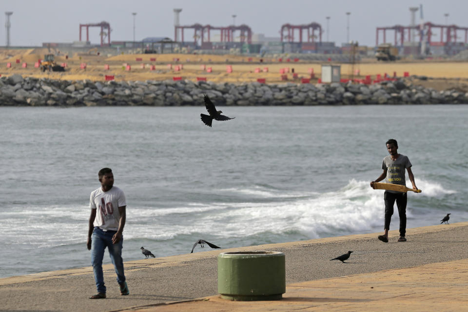 FILE - In this Nov. 3, 2018, file photo, Sri Lankan men walk along the shore near the Chinese funded sea reclamation project in Colombo, Sri Lanka. China's loans to poor countries in Africa and Asia impose unusual secrecy and repayment terms that are hurting their ability to renegotiate debts after the coronavirus pandemic, a group of U.S. and German researchers said in a report Wednesday, March 31, 2021. (AP Photo/Eranga Jayawardena, File)