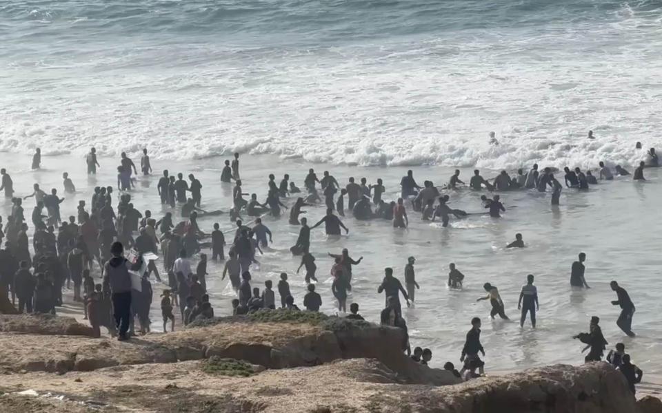 Palestinians wading into the sea off Gaza to collect aid dropped in the US initiative