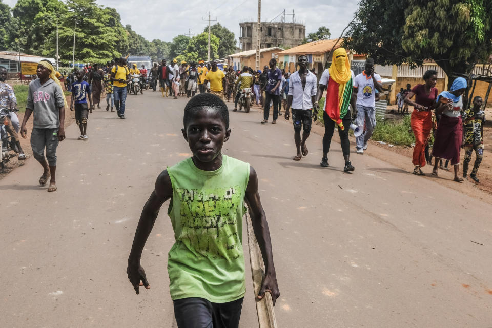 Supporters of the ruling Rally of the Guinean People (RPG) party demonstrate against the opposition Union of Democratic Forces of Guinea (UFDG) party and block the visit of their leader, in the streets of Kankan, Guinea Sunday, Oct. 11, 2020. The stage is set for Oct. 18 presidential elections pitting incumbent President Alpha Conde, 82, who is bidding for a third term, against opposition leader Cellou Dalein Diallo, who was previously defeated by Conde in both the 2010 and 2015 elections. (AP Photo/Sadak Souici)