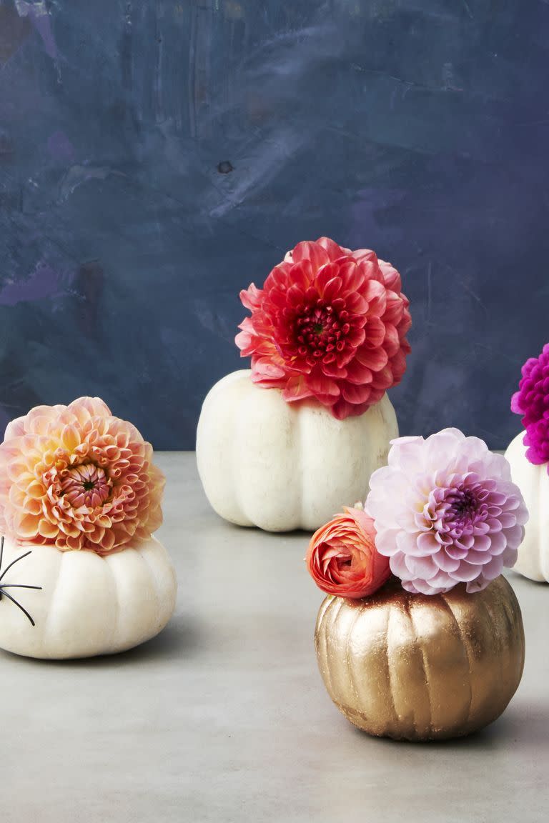<p>Ditch the kitschy Halloween decor for a sophisticated centerpiece, like mini gourds that can double as vases. Fill carved pumpkins with water bottles (cut the bottoms off) and add ranunculuses, mums and dahlias. </p>