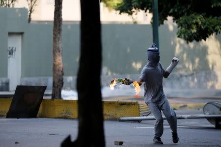 An opposition supporter prepares to throw a molotov cocktail during a clash with security forces in a rally against Venezuela's President Nicolas Maduro in Caracas, Venezuela, April 26, 2017. REUTERS/Carlos Garcia Rawlins