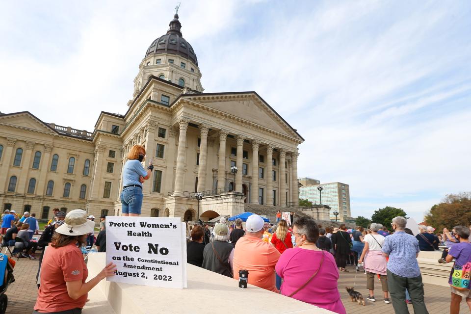 A women holds a sign asking voters to vote no on an upcoming amendment to the Kansas Constitution regarding abortion during the National Women's March on Oct. 2.