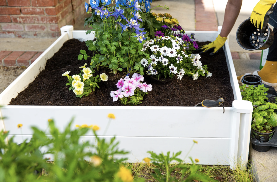 Outdoor Planter Box in white filled with soil and flowers (Photo via Wayfair)