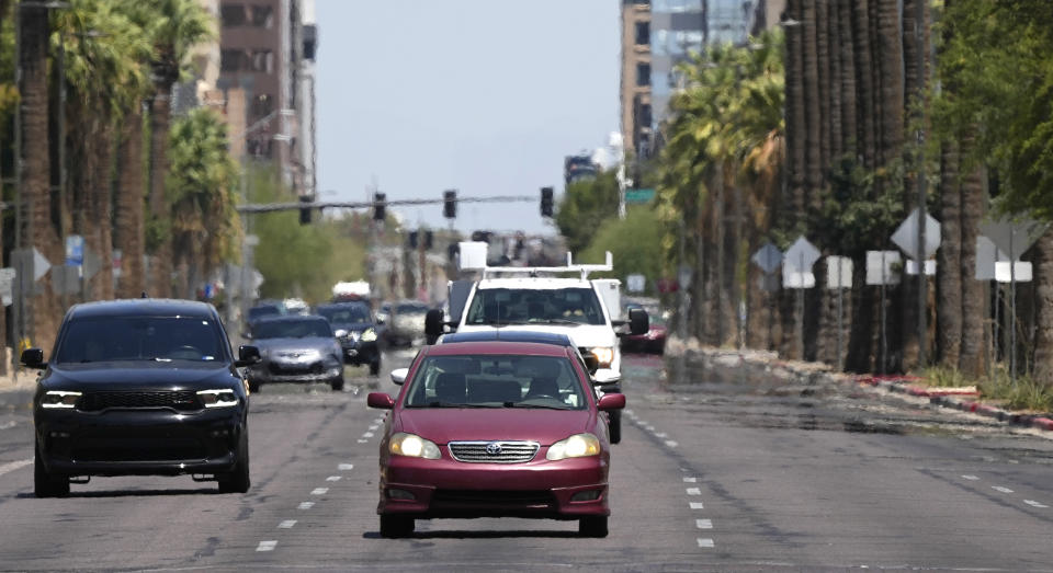 Heat waves rise off the pavement as vehicles drive along a downtown street as temperatures are expected to hit 115-degrees Fahrenheit, Tuesday, July 18, 2023, in Phoenix. Tuesday marks a new record for the most consecutive days in a row over 110-degrees. (AP Photo/Ross D. Franklin)