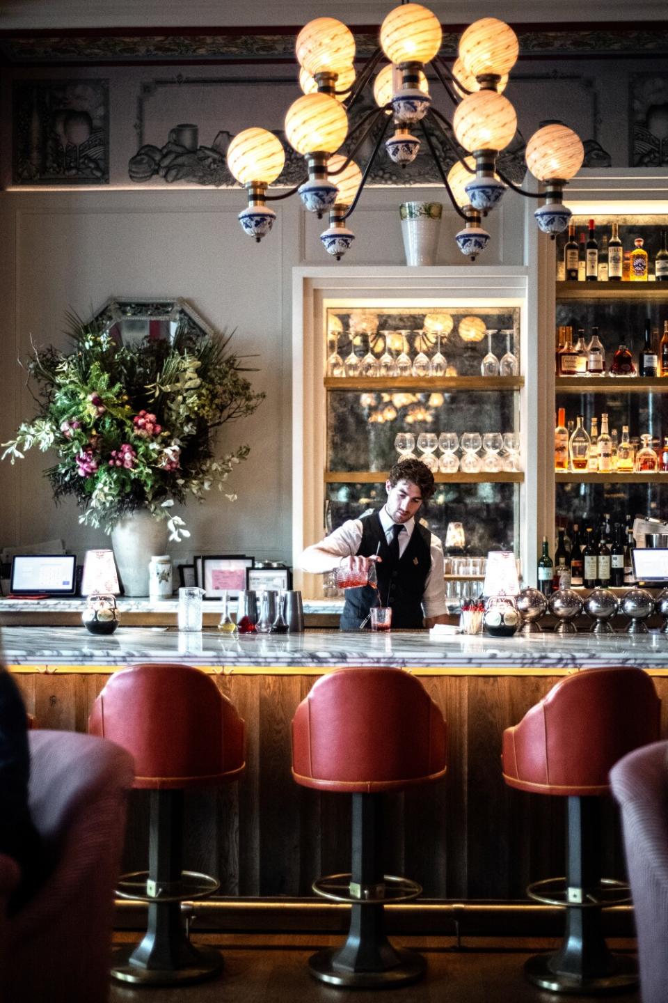 A marble-topped bar with a globe chandelier overhead.