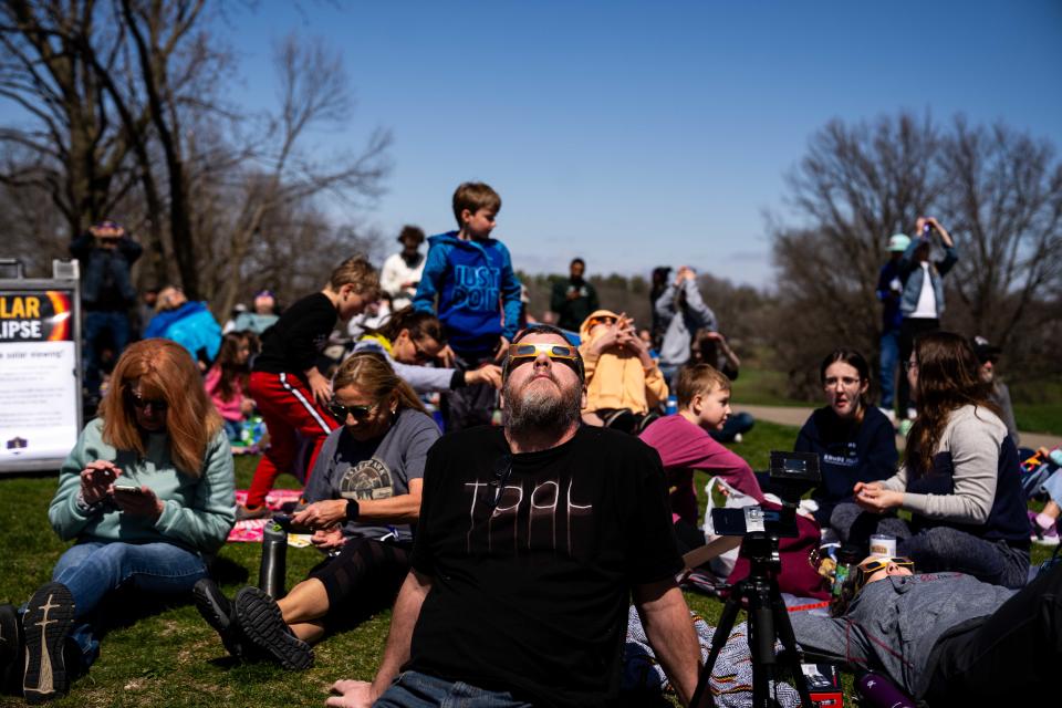 Iowans look to the sky through their solar eclipse glasses as the eclipse reaches its peak Monday, April 8, 2024, at the Drake Municipal Observatory.