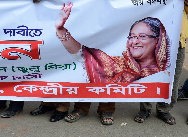Supporters of Bangladeshi Prime Minister Sheikh Hasina hold a banner showing her image during a rally in front of her political party's headquarters in Dhaka on January 4, 2014