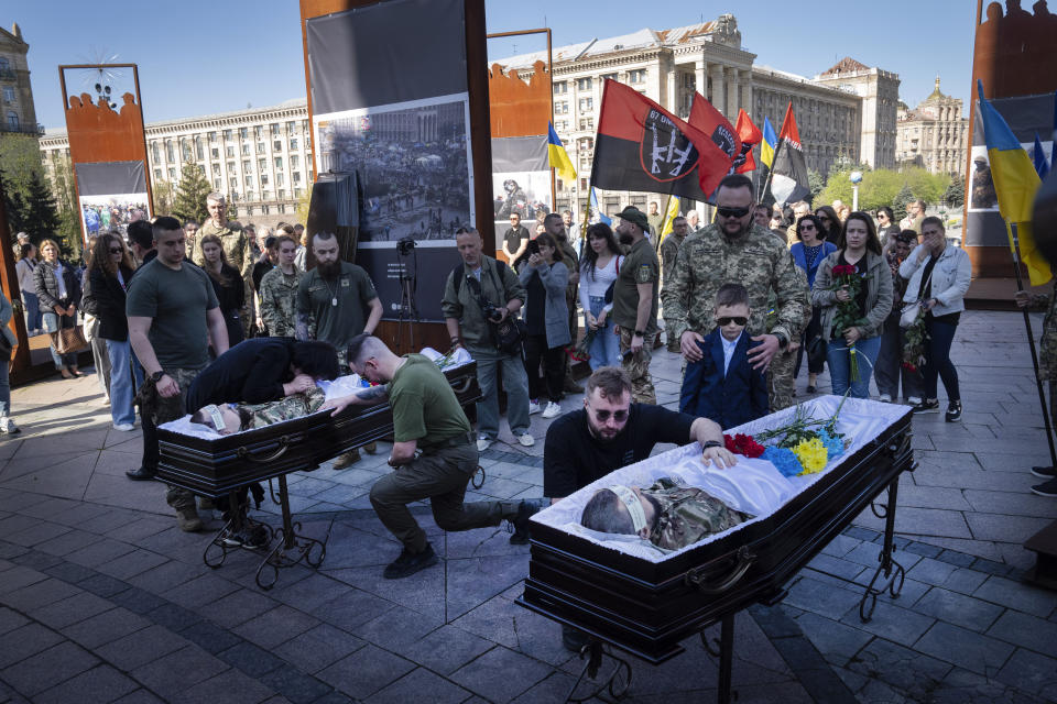 People pay respect at the coffins of Ukrainian servicemen Serhiy Konoval and Taras Petrushun, who were killed in a battle with the Russian troops, during the funeral ceremony in Independence square in Kyiv, Ukraine, Tuesday, April 9, 2024. (AP Photo/Efrem Lukatsky)