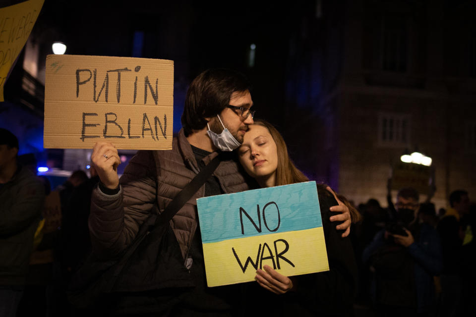 Several people hold banners at a rally in front of the Russian embassy in Barcelona.