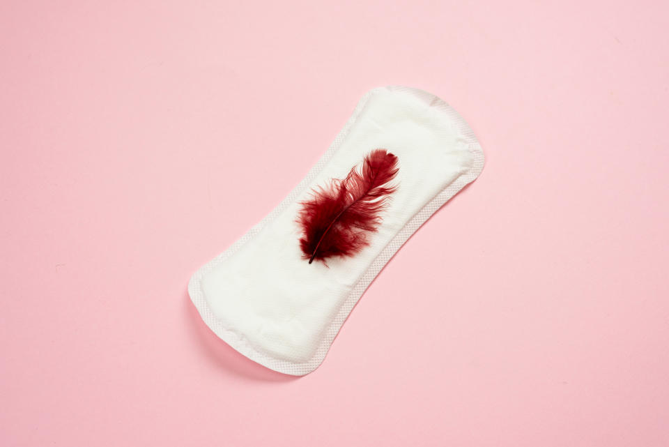 Menstruation. White woman lying on pink background. Female lining with red feather. Women's critical days.