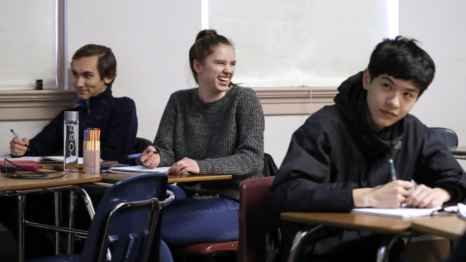 Senior Hazel Ostrowski, center, smiles as she looks up during her first period, AP statistics class at Franklin High School Wednesday, Dec. 12, 2018, in Seattle. High school students are getting more sleep in Seattle, according to a study on later school start times. Ostrowski was among a group at Franklin and another Seattle high school who wore activity monitors to discover whether a later start to the school day would help them get more sleep. It did, adding 34 minutes of slumber a night, and they reported less daytime sleepiness and grades improved. (AP Photo/Elaine Thompson)