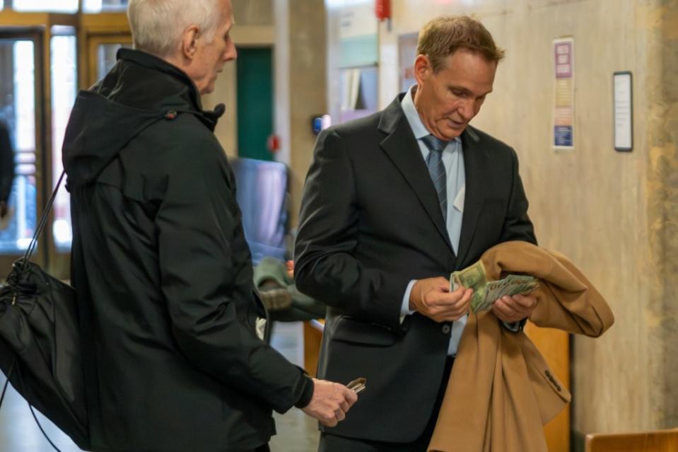 Michael Spillane thumbs through a wad of cash next to his attorney after his court appearance Monday.