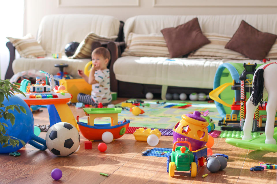 Toddler playing amongst many toys in a messy room