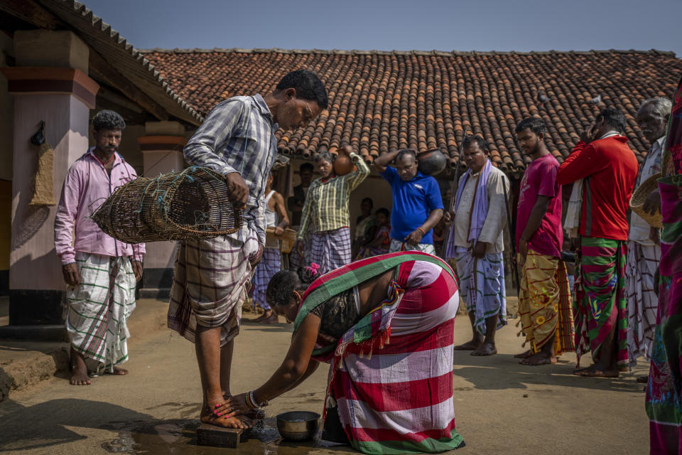 A tribe woman washes the feet of worshippers upon their arrival from a sacred grove believed to be the home of the village goddess, in village Guduta, in the eastern Indian state of Odisha, Oct. 21, 2022. India's 110 million indigenous tribespeople scattered across various states and fragmented into hundreds of clans, with different legends, different languages and different words for their gods adhere to Sarna Dharma - a faith not officially recognized by the government. It is a belief system that shares common threads with the world's many ancient nature-worshipping religions. (AP Photo/Altaf Qadri)