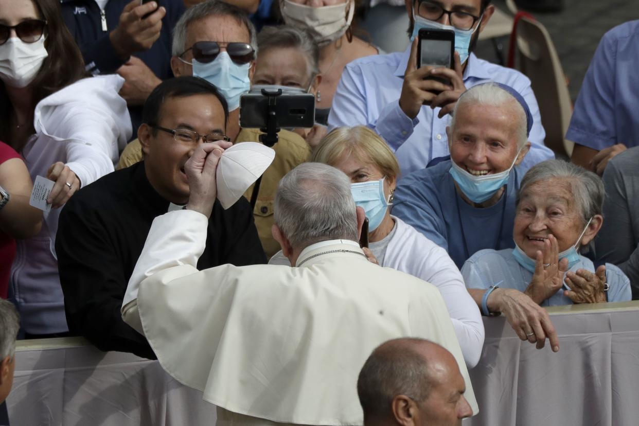 Pope Francis holds a skull cap as he tours the crowd at the start of his first general audience with the faithful since February when the coronavirus outbreak broke out, in the San Damaso courtyard at the Vatican on Wednesday, Sept. 2, 2020.