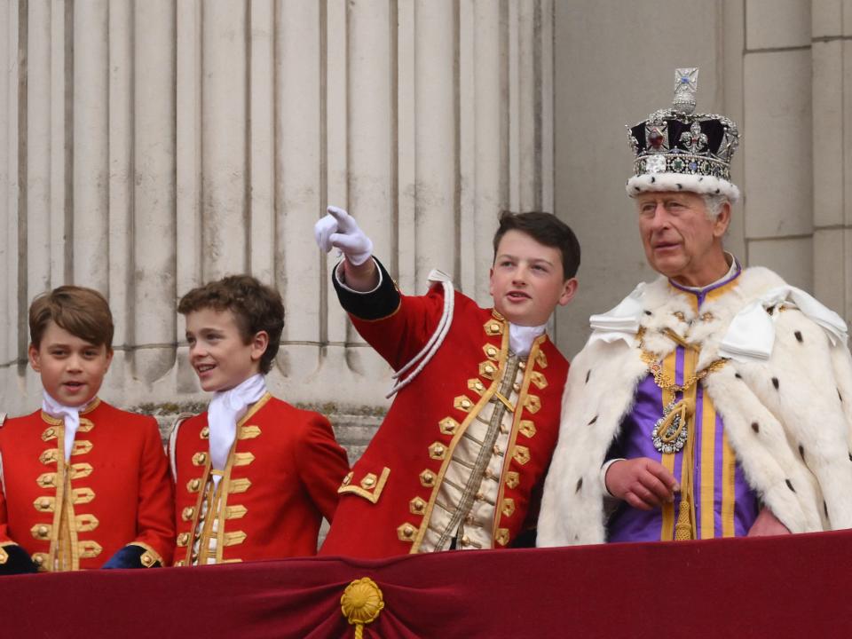 A page of honor speaks with Britain's King Charles on the Buckingham Palace balcony