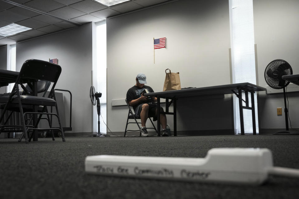 Charlie Reyes reads in cooling center Saturday, May 18, 2024, at Tracy Gee Community Center in Houston. "I was at a loss, I didn't know what to do other than go hide," he said of the storm. "Since then it's been trying to keep myself OK." He said he was at the center to charge his devices. "My poor car can only charge so much." (Jon Shapley/Houston Chronicle via AP)