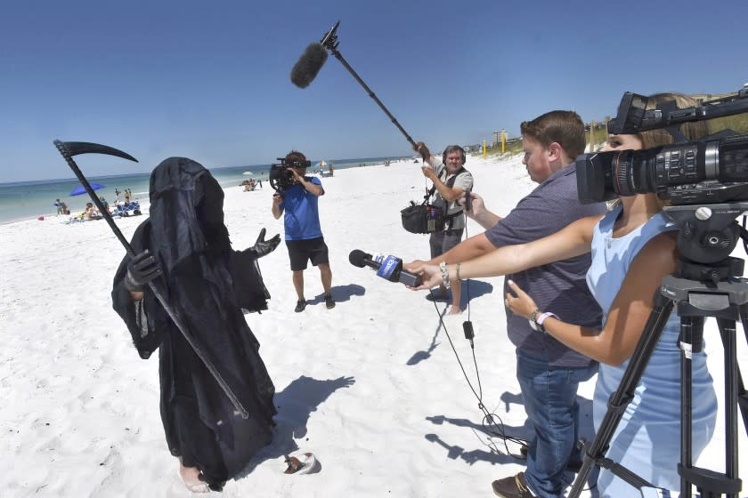 Florida Attorney Daniel Uhlfelder, dressed as the Grim Reaper, talks with reporters after walking the newly-opened beach near Destin, Fla., Friday, May 1, 2020. Uhlfelder was protesting the Walton County, Fla., Commission's decision to reopen the county's beaches in spite of the COVID-19 pandemic. "In these circumstances, I can see no rational reason to open our beaches, effectively inviting tens of thousands of tourists back into our community," Uhlfelder said in a news release. "If by dressing up as the "Grim Reaper" and walking our beaches I can make people think and potentially help save a life – that is the right thing to do." (Devon Ravine/Northwest Florida Daily News via AP)