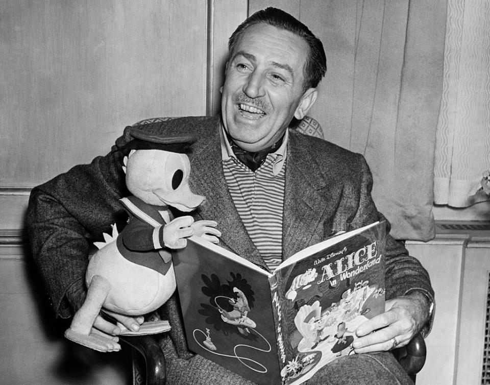 Walt Disney holding a stuffed Donald Duck and "Alice in Wonderland" book