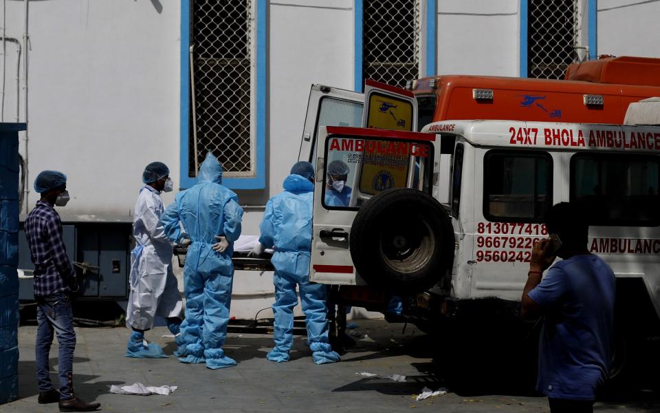  Health workers and relatives wearing personal protection equipment (PPE) move the body of a Covid-19 fatality - Amarjeet Kumar Singh/Anadolu Agency via Getty Images